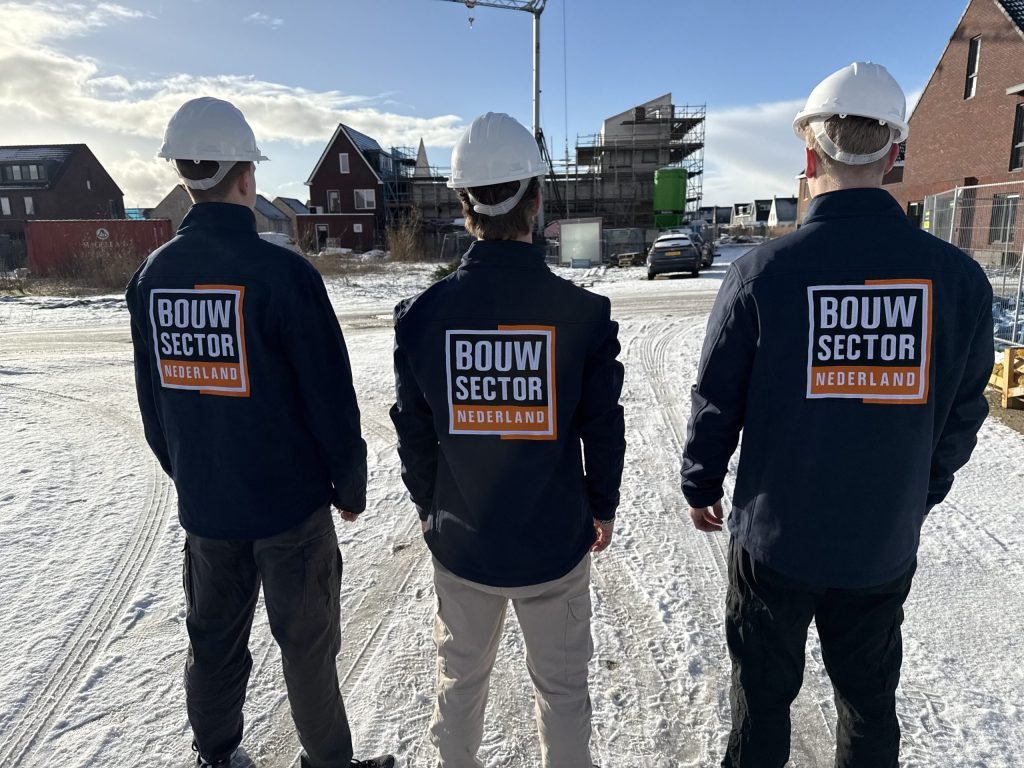 Drie vakmensen van Bouwsector Nederland met witte helm op een nieuwbouwlocatie in de sneeuw